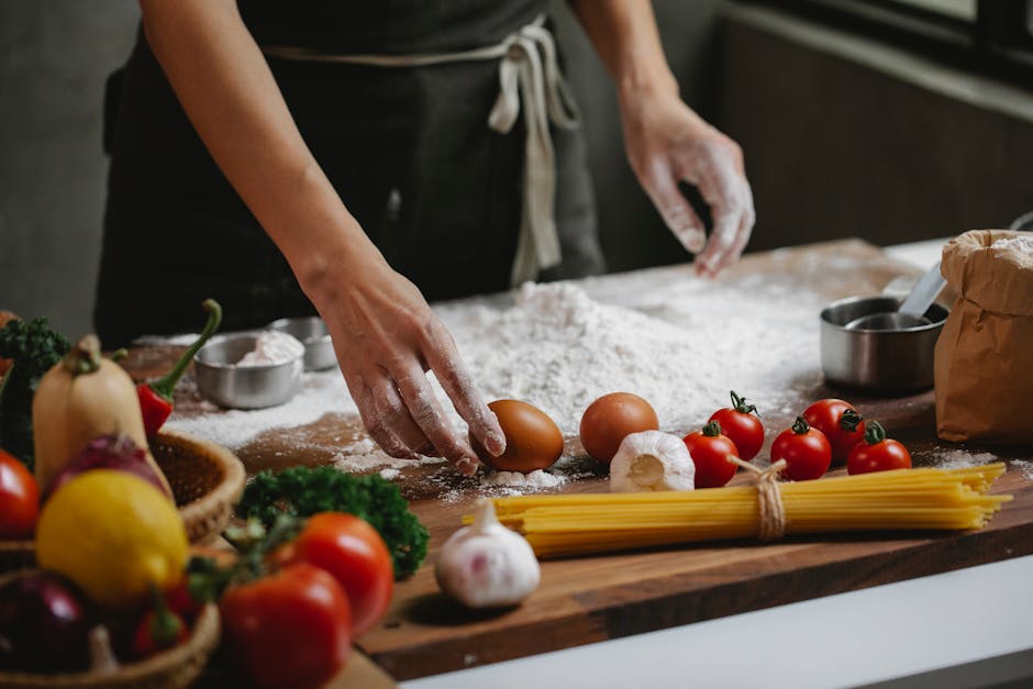 High angle of crop anonymous chef preparing meal consisting of eggs garlic cherry tomatoes and spaghetti